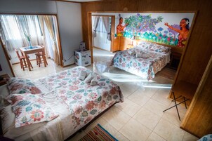 Habitación de hotel con dos camas, un escritorio y una silla. Hay un cuadro en la pared y una ventana con cortinas.