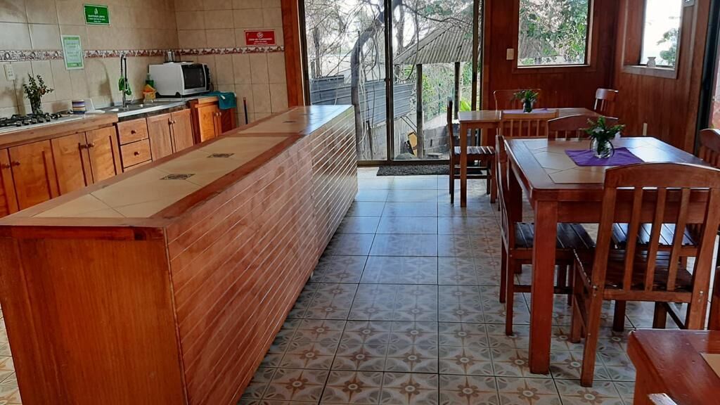 A kitchen with wooden cabinets, a central island, and a dining area with wooden tables and chairs.