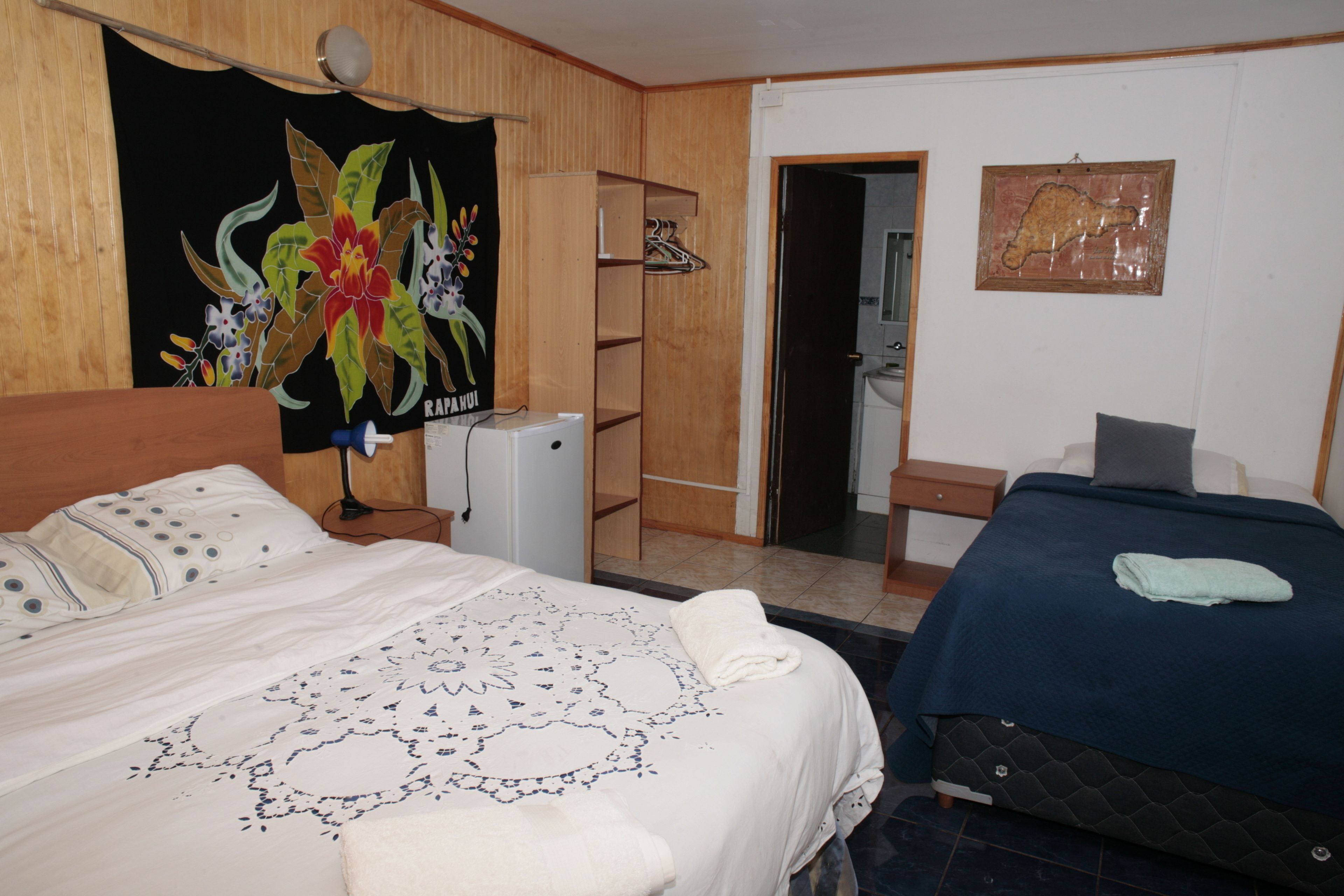 A hotel room with a bed, a desk, a wardrobe, and a bathroom visible through an open door.