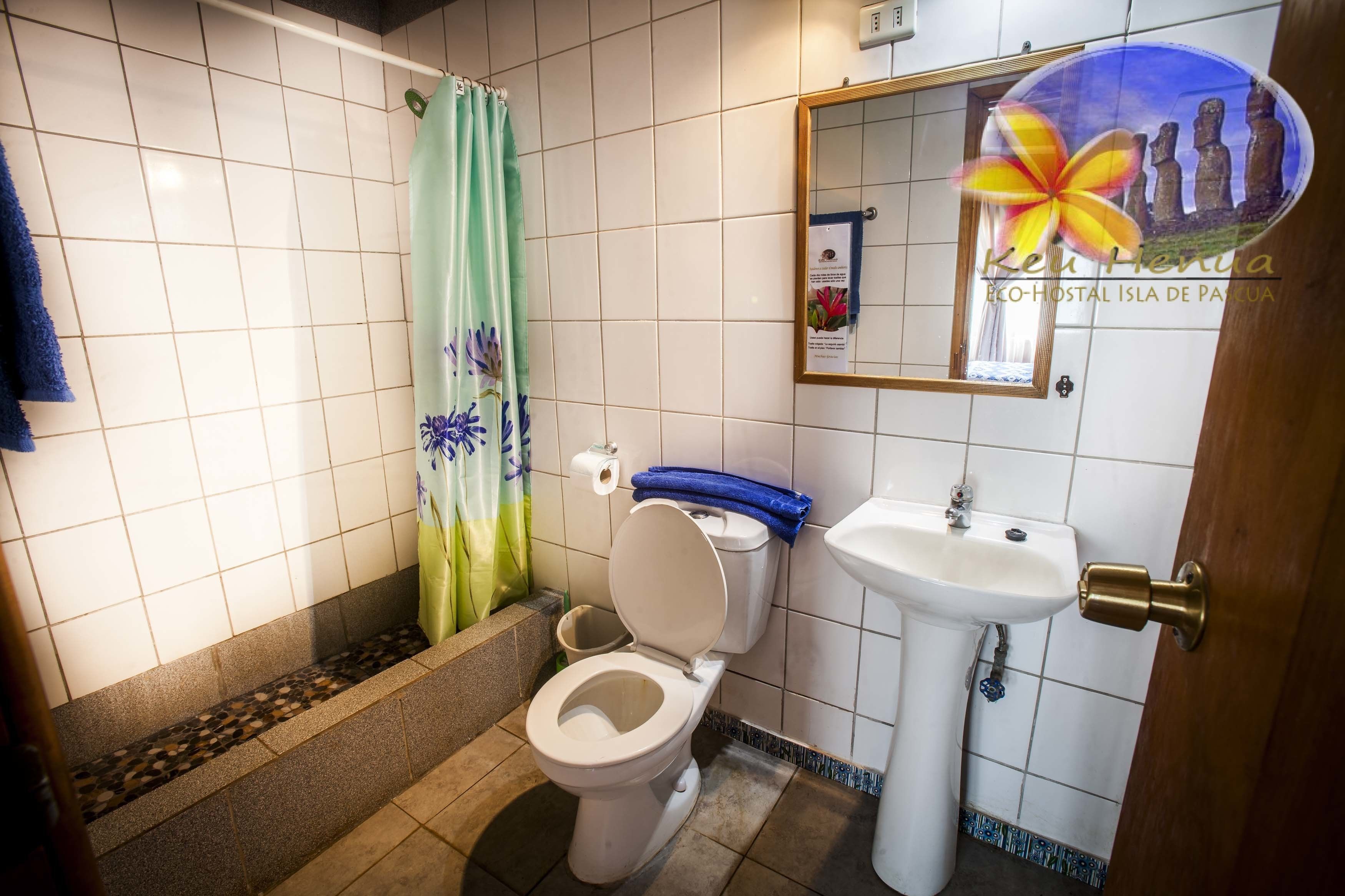 Et badeværelse med toilet, vask og bruseforhæng.
