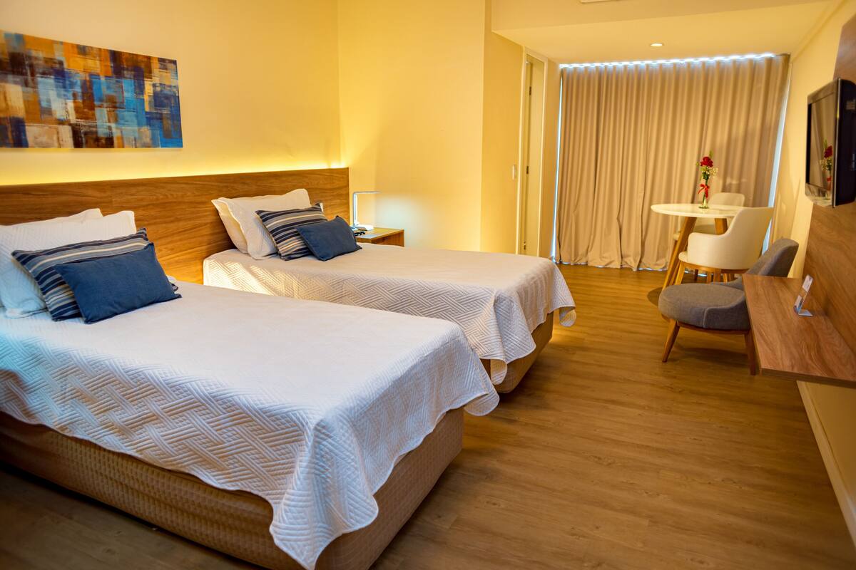 Een hotelkamer met twee bedden, een bureau, een stoel en een televisie.