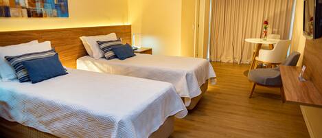 Ein Hotelzimmer mit zwei Betten, einem Schreibtisch, einem Stuhl und einem Fernseher.