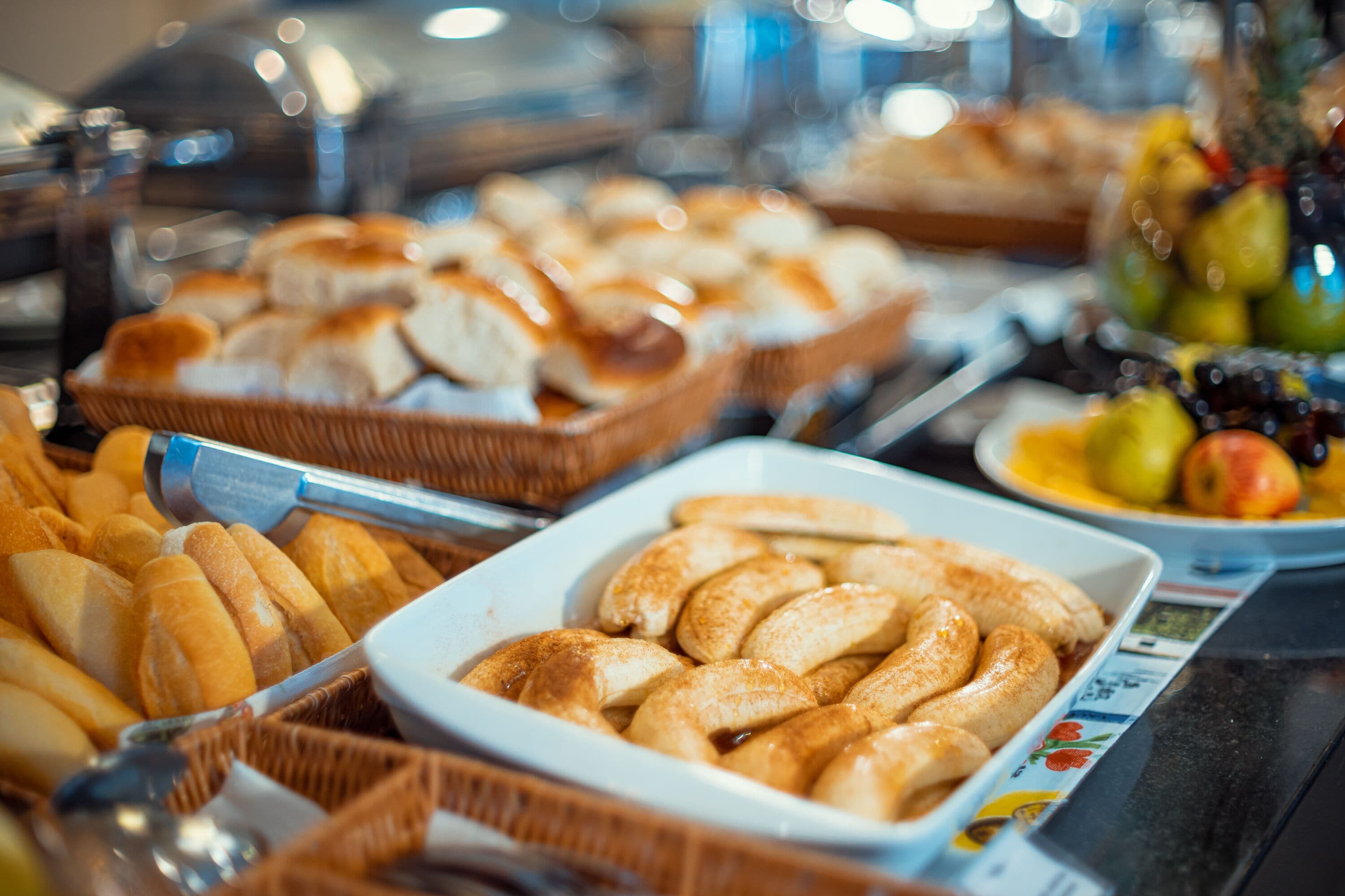 A buffet with various food items including bread, pastries, and fruits.