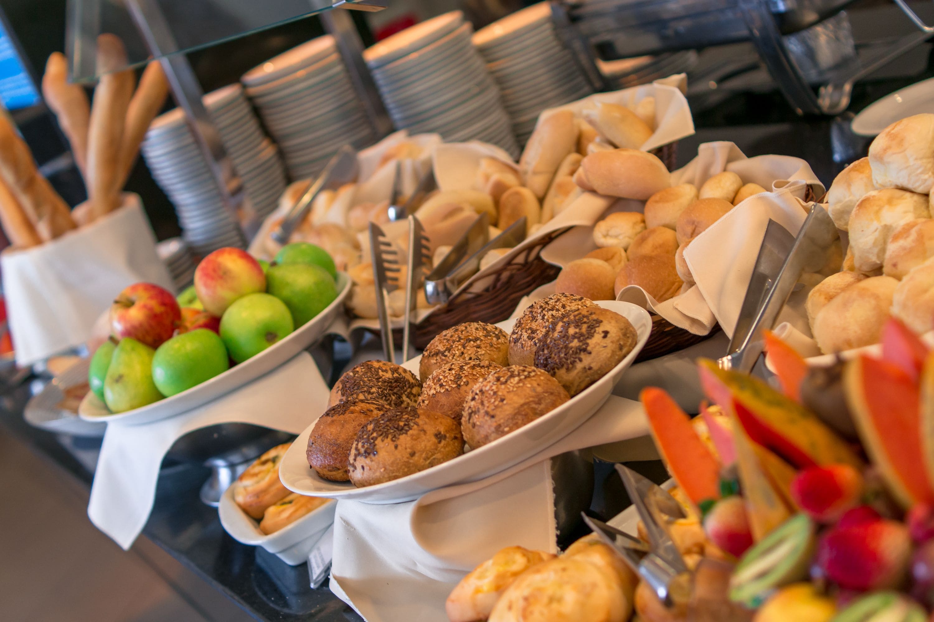 A buffet with various food items including bread, pastries, and fruits.