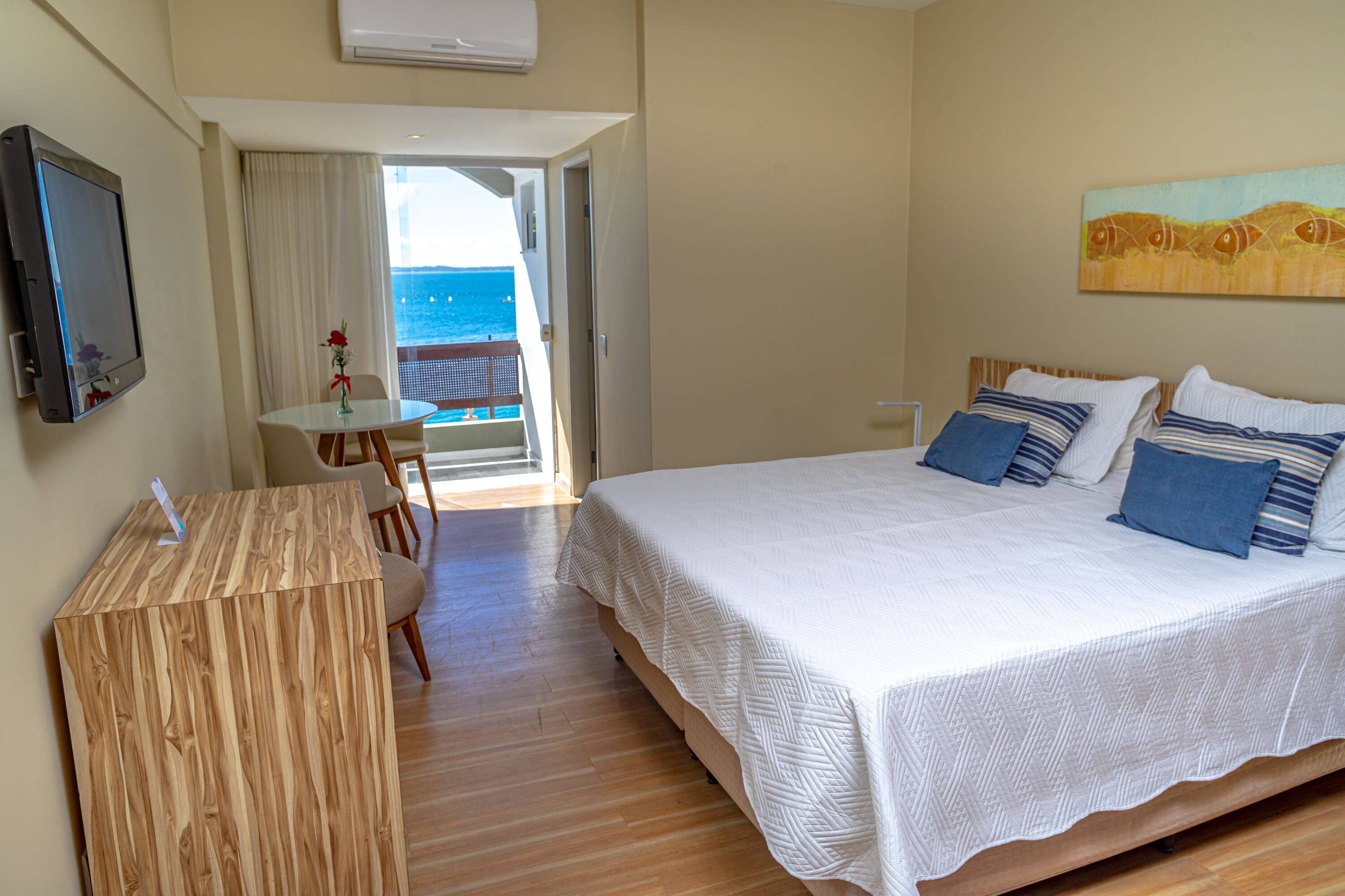 Habitació d'hotel amb llit, escriptori i balcó amb vista al mar.