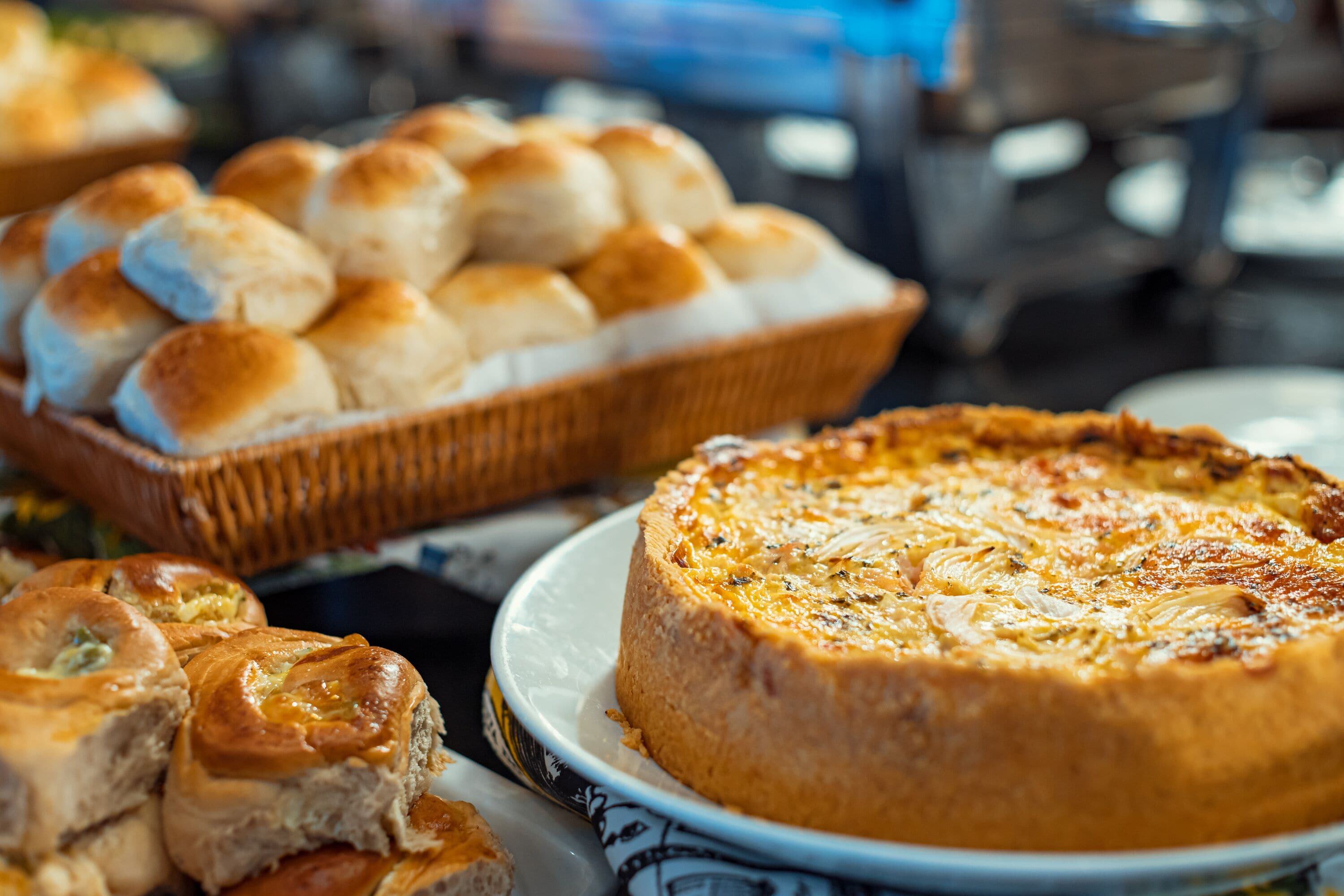 Diverse gebakjes, waaronder een quiche, broodjes en patisserie, op een tafel.