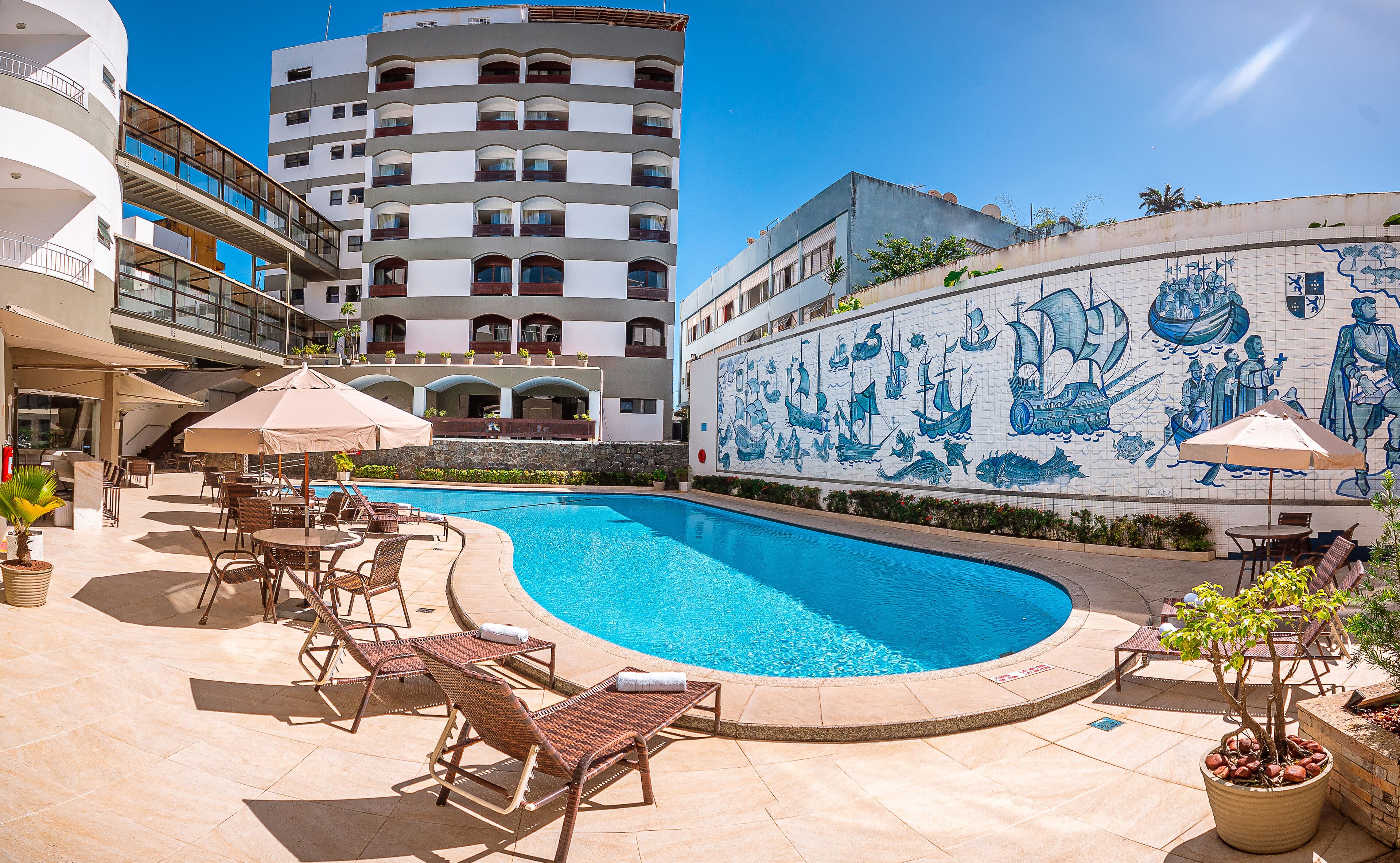 A swimming pool with lounge chairs and umbrellas, surrounded by a tiled patio area.