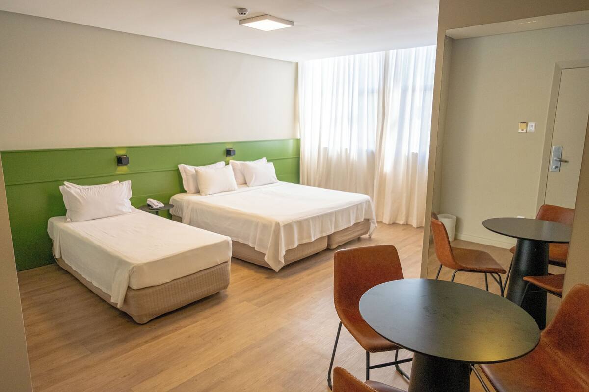 Een hotelkamer met twee bedden, een eettafel en een stoel.