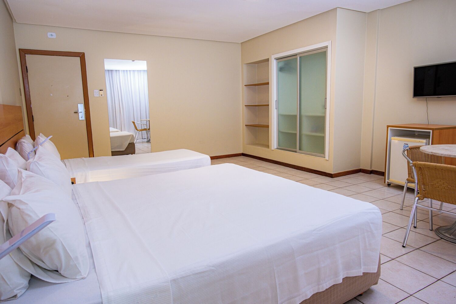 Een hotelkamer met twee bedden, een televisie, een klein tafeltje en een kledingkast.