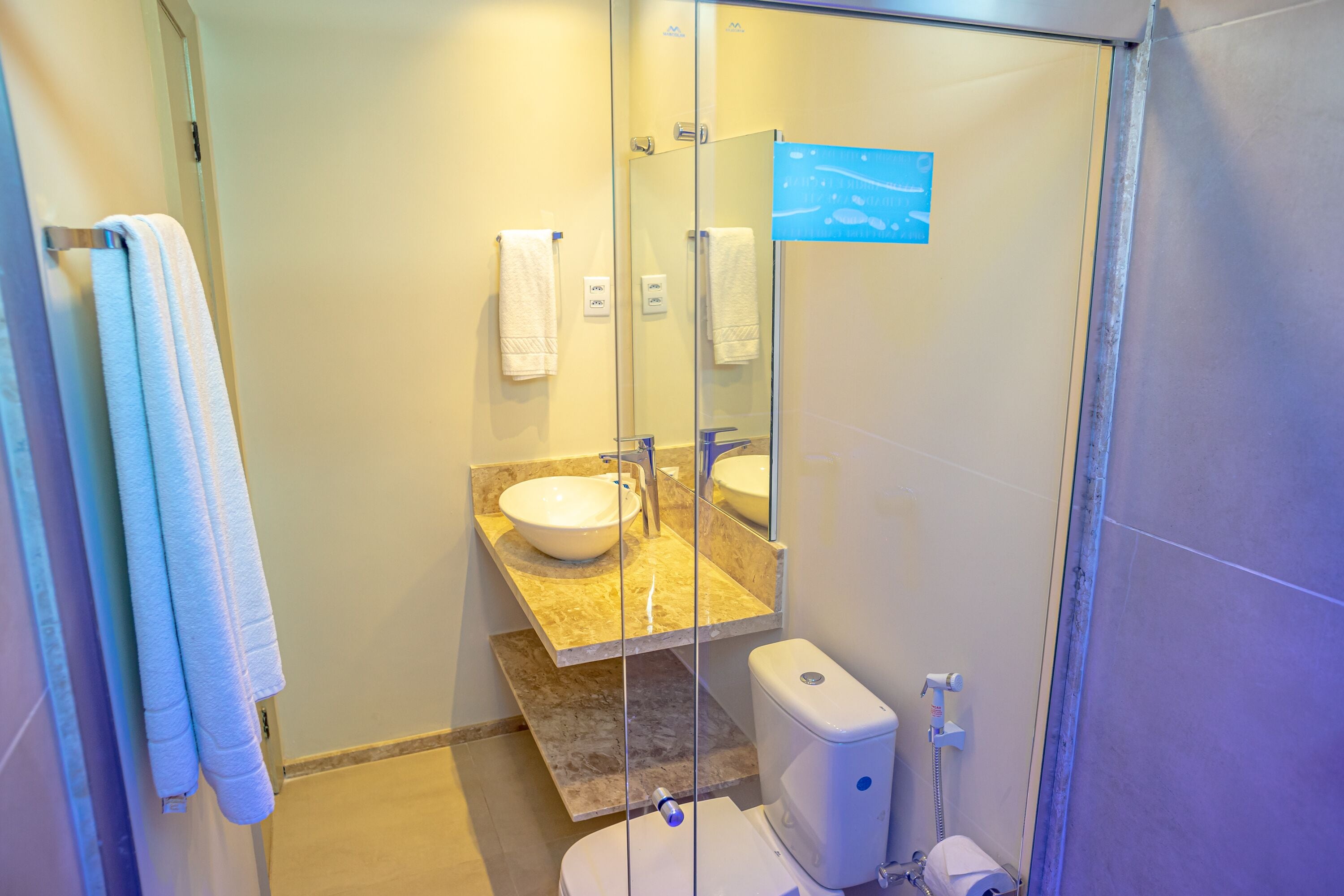 Ein modernes Badezimmer mit einer Duschkabine aus Glas, einer weißen Toilette und einem Waschtisch mit Waschbecken und Spiegel.