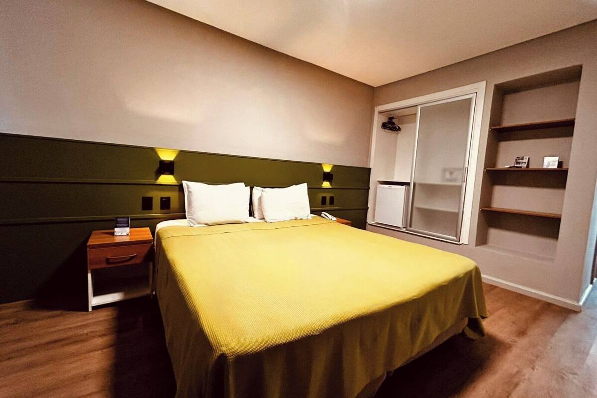 Een hotelkamer met een bed, nachtkastjes, een garderobe en een bedtafel.