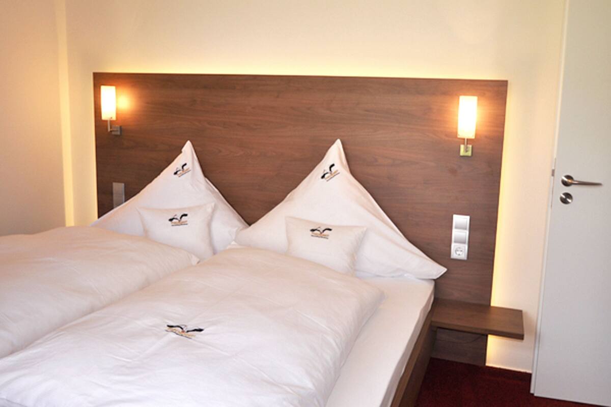 A double bed with a wooden headboard, two bedside lamps, and a small nightstand.