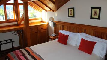 A bedroom with a large bed, wooden headboard, and a window with a view of buildings.