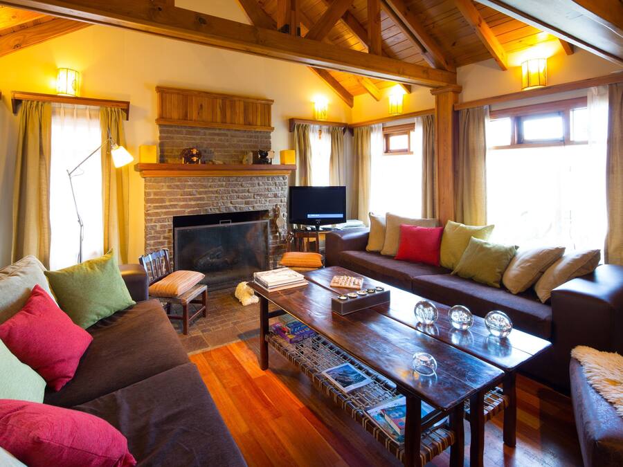 A cozy living room with a fireplace, wooden beams, and comfortable seating.