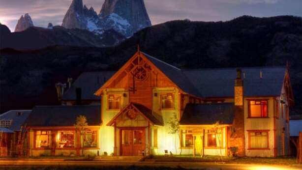 A large, multi-story building with a prominent central tower, surrounded by smaller structures. - Hostería Senderos (El Chalten)
