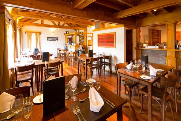 A restaurant with wooden interiors, multiple dining tables, and chairs. - Hostería Senderos (El Chalten)