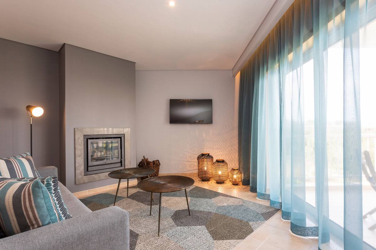 A modern living room with a sofa, coffee table, fireplace, and decorative items.