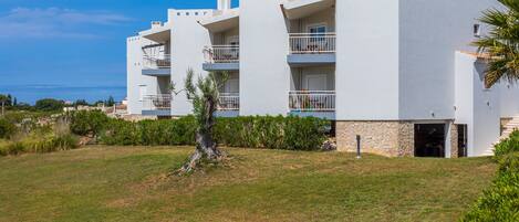 Un moderno edificio a più piani con balconi, una base in pietra e vista sul mare.
