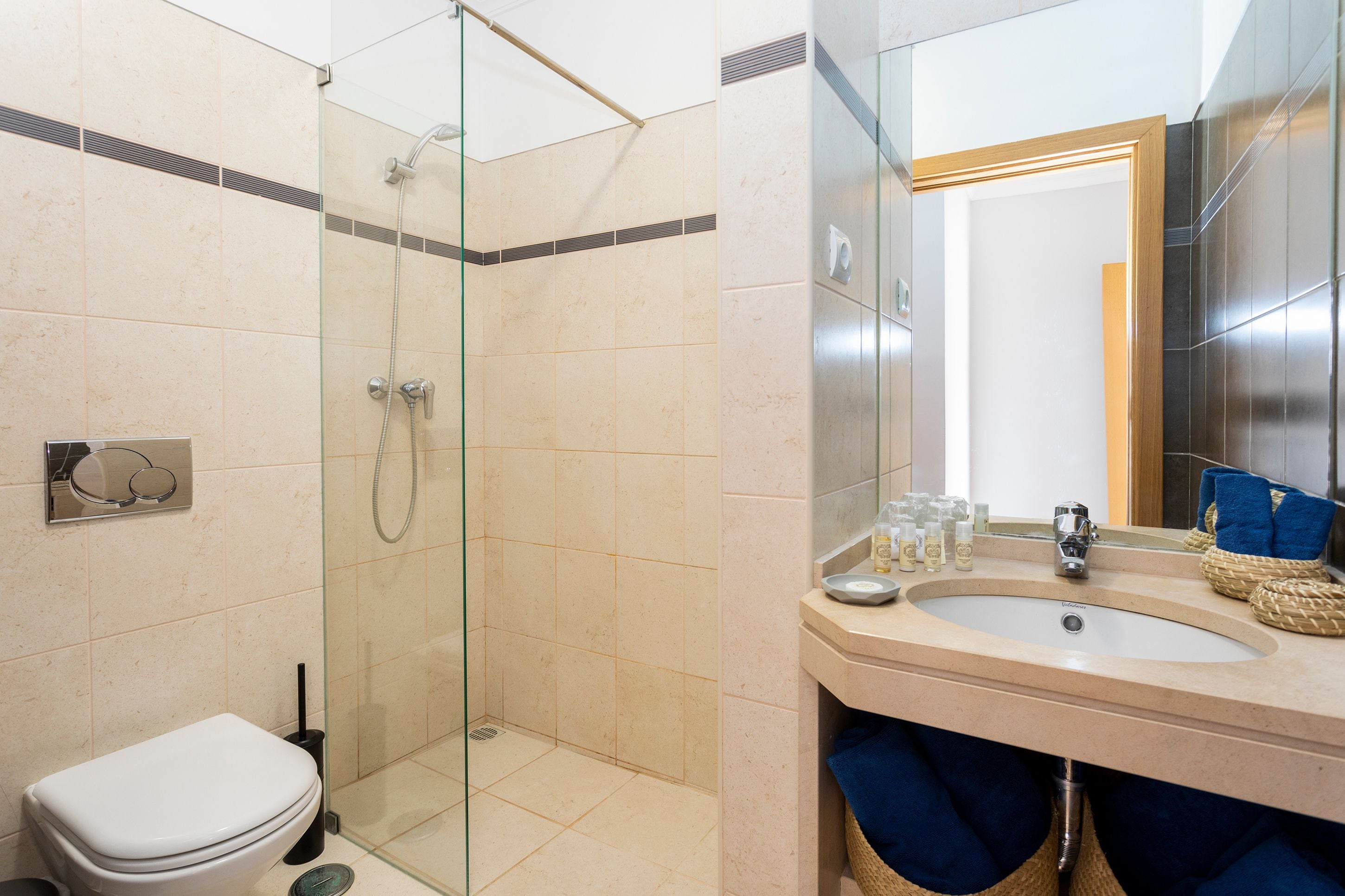 A bathroom with a glass-enclosed shower, a toilet, and a sink with a mirror.