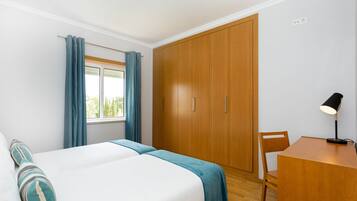 Um quarto com cama, escrivaninha e guarda-roupa.