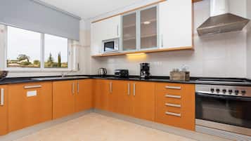 Una cocina moderna con armarios de madera, microondas integrado, cafetera y estufa.