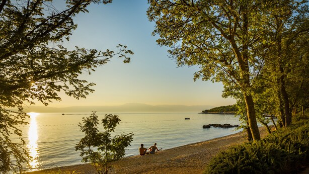 A lakeside scene with a clear sky, calm water, and a few boats. - Magal Maradiso Hotel by Aminess  (Omisalj)