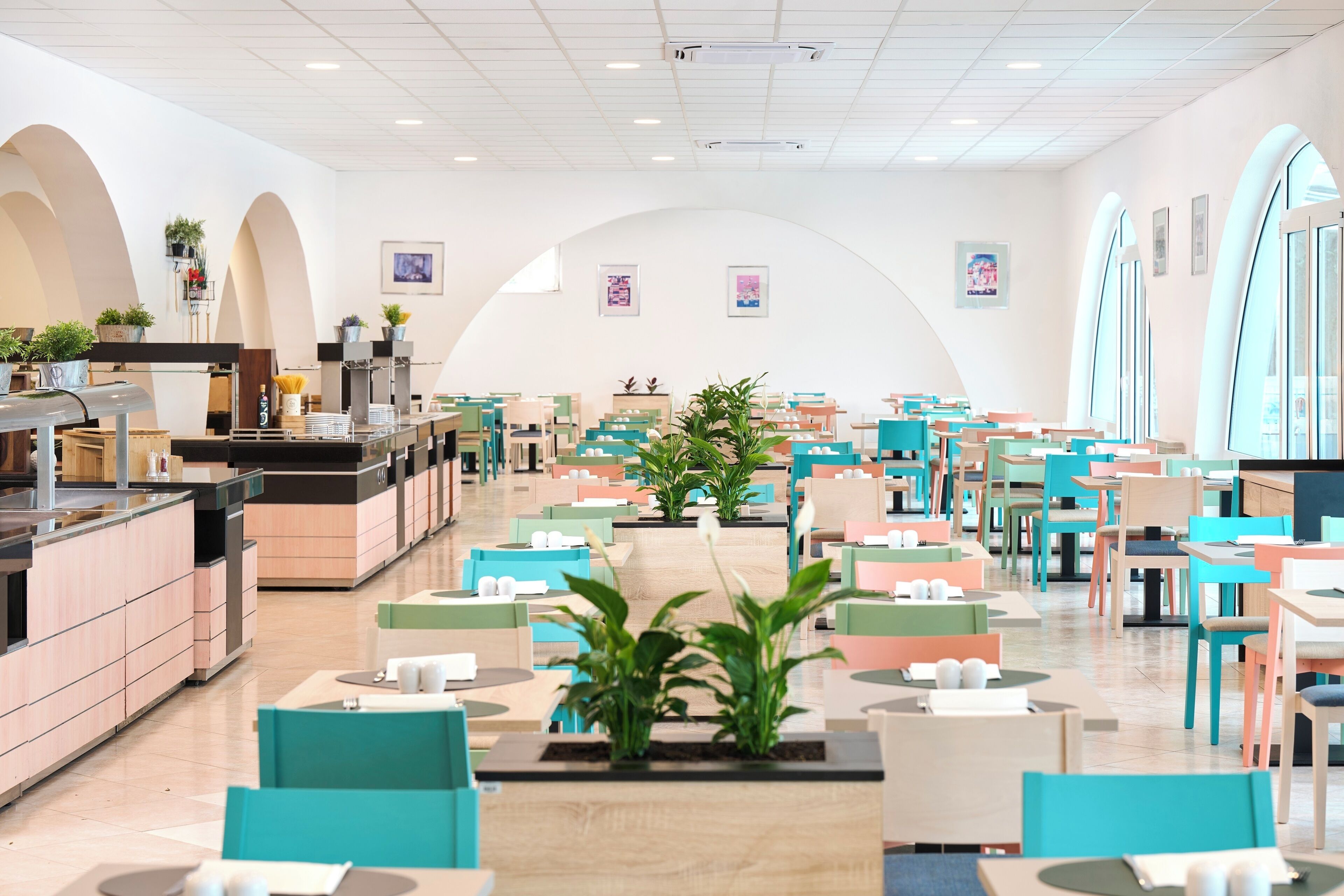 A modern restaurant with a central seating area, a kitchen on the left, and a bar area.