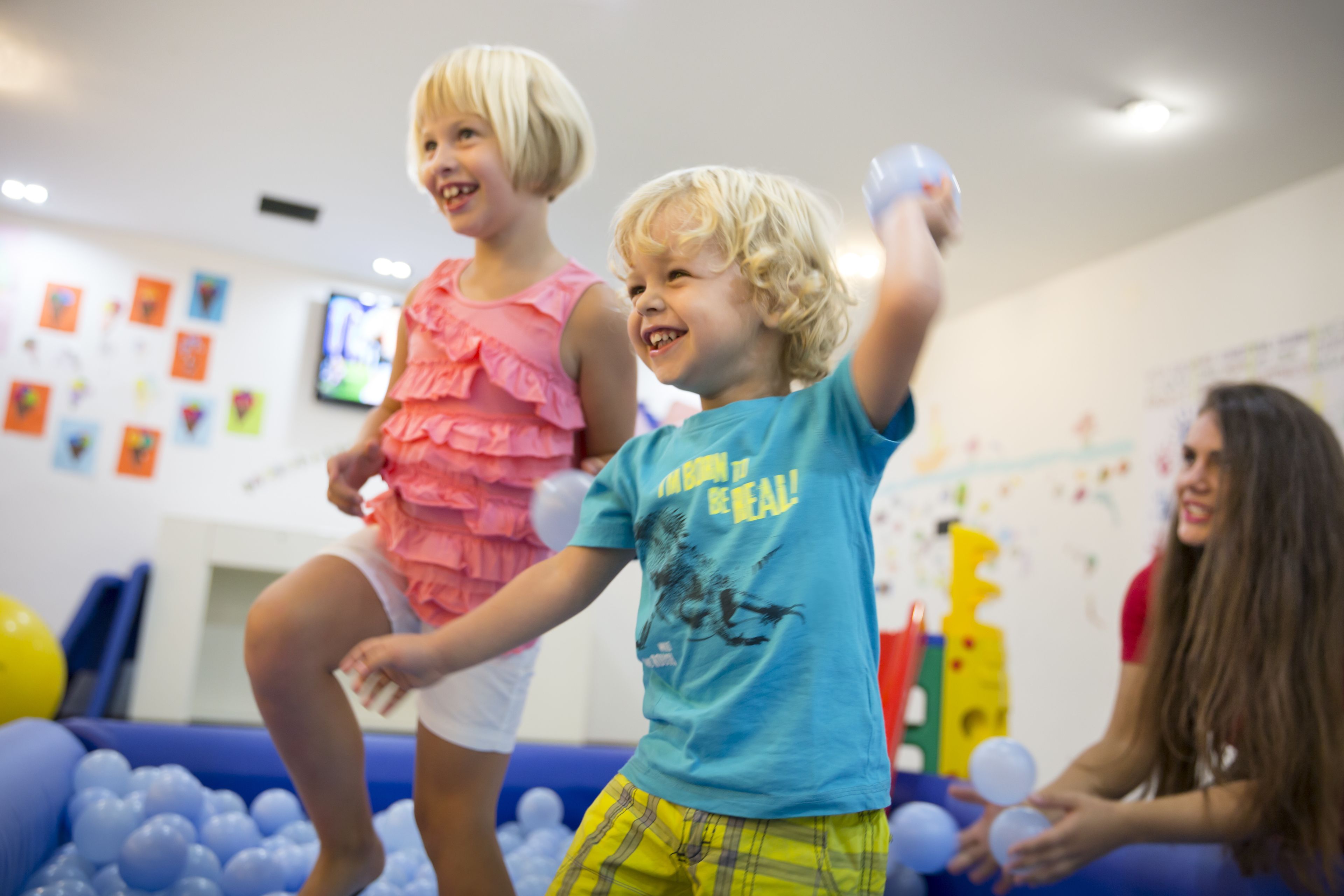 Des enfants jouent dans une pièce décorée de couleurs vives et qui contient une piscine à balles.