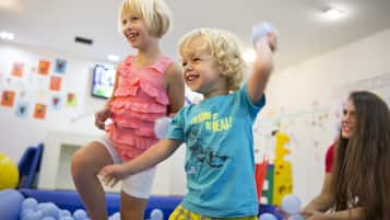 Des enfants jouent dans une pièce décorée de couleurs vives et qui contient une piscine à balles.