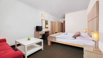 Une chambre d’hôtel comprenant un lit, un bureau, une chaise, une télévision et une armoire.