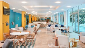 A modern hotel lobby with a bar area, seating arrangements, and large windows offering views. - Magal Maradiso Hotel by Aminess  (Omisalj)