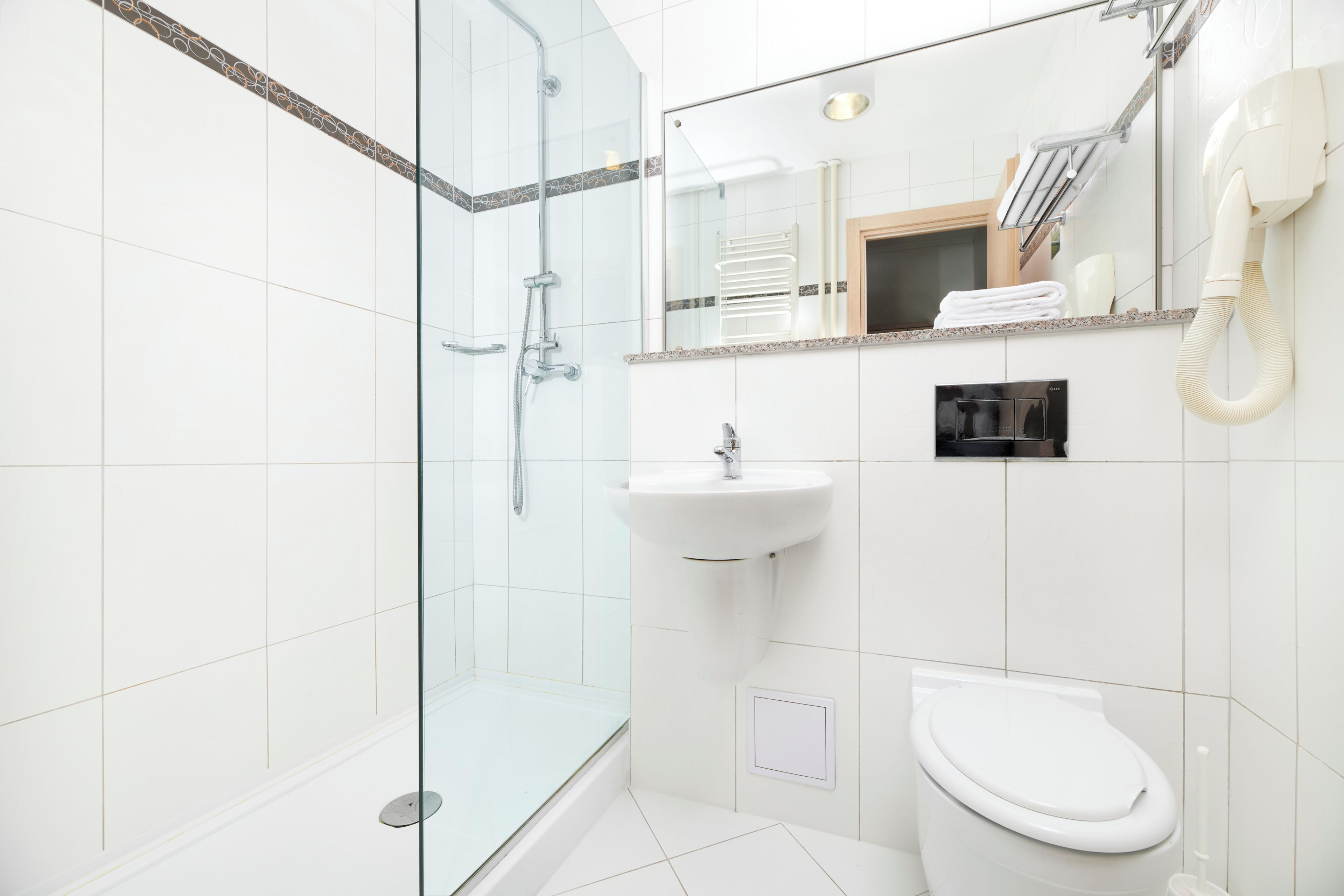 Un baño moderno con cabina de ducha de vidrio, un lavabo blanco y un inodoro.