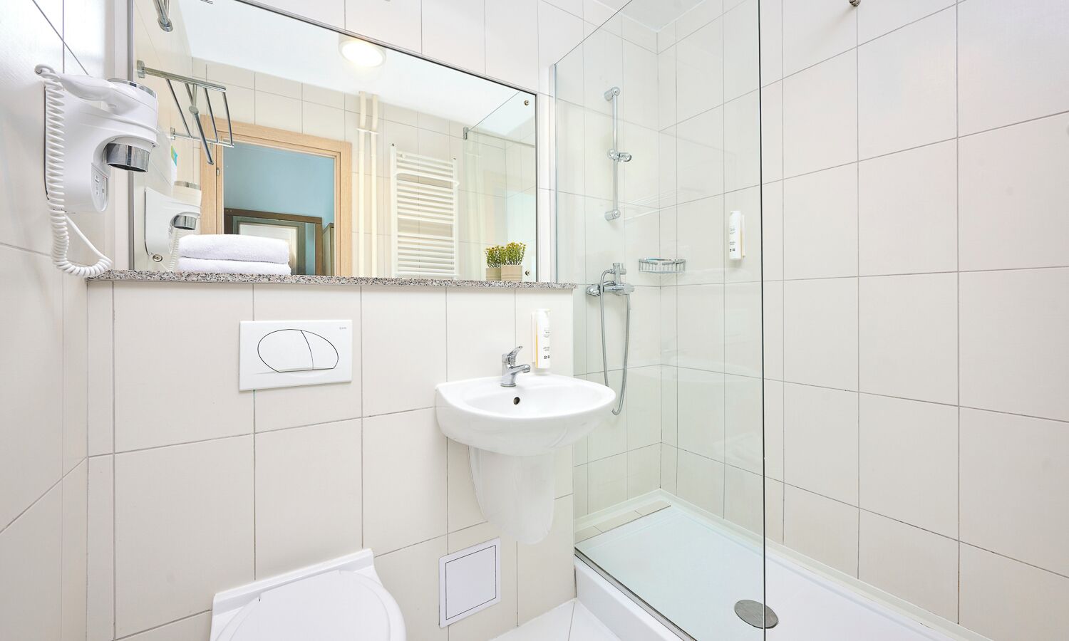A modern bathroom with a glass shower enclosure, a white sink, and a towel rack.