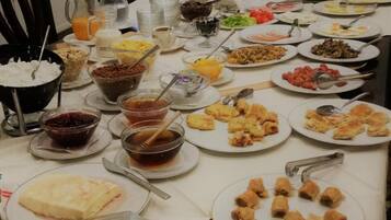Taula de buffet amb diversos plats i begudes, una escala al fons i un penjador.