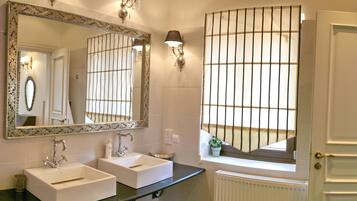 Un baño con dos lavamanos, un espejo grande y apliques de pared.