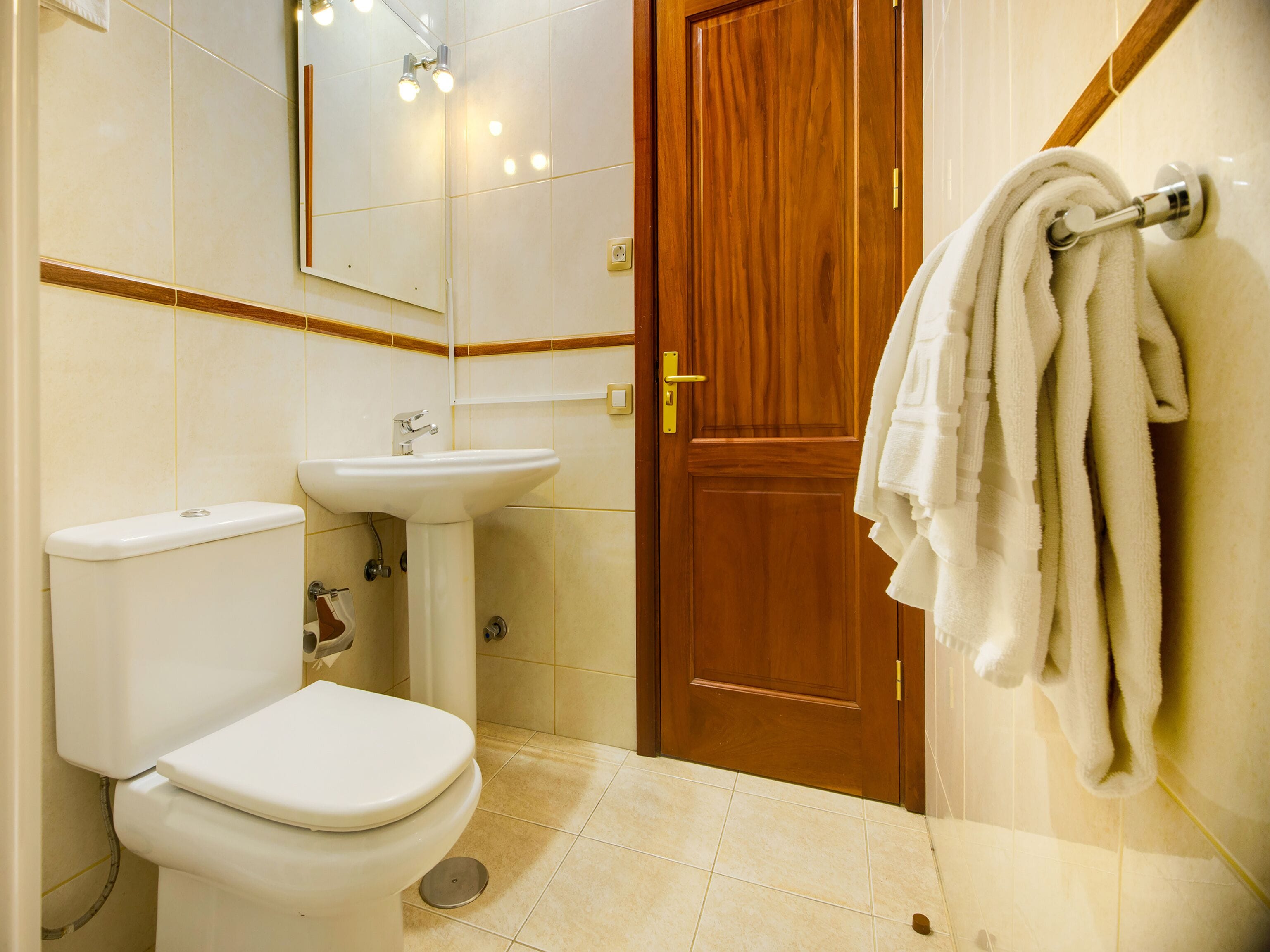 A bathroom with a toilet, sink, and wooden door.