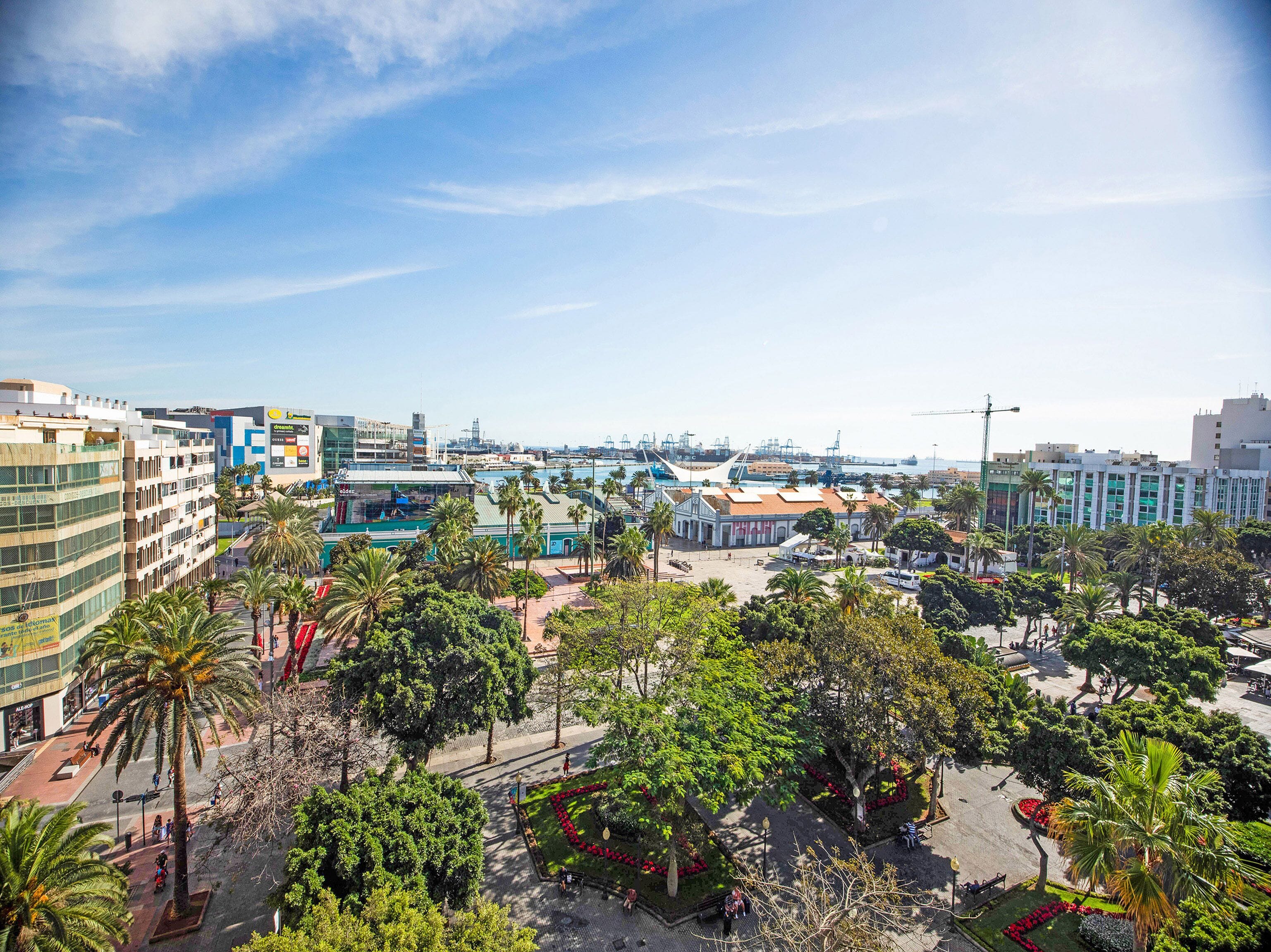 A cityscape with modern buildings, a marina, and a central park with palm trees.