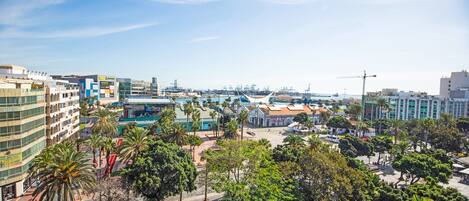 A cityscape with modern buildings, a marina, and a central park with palm trees.