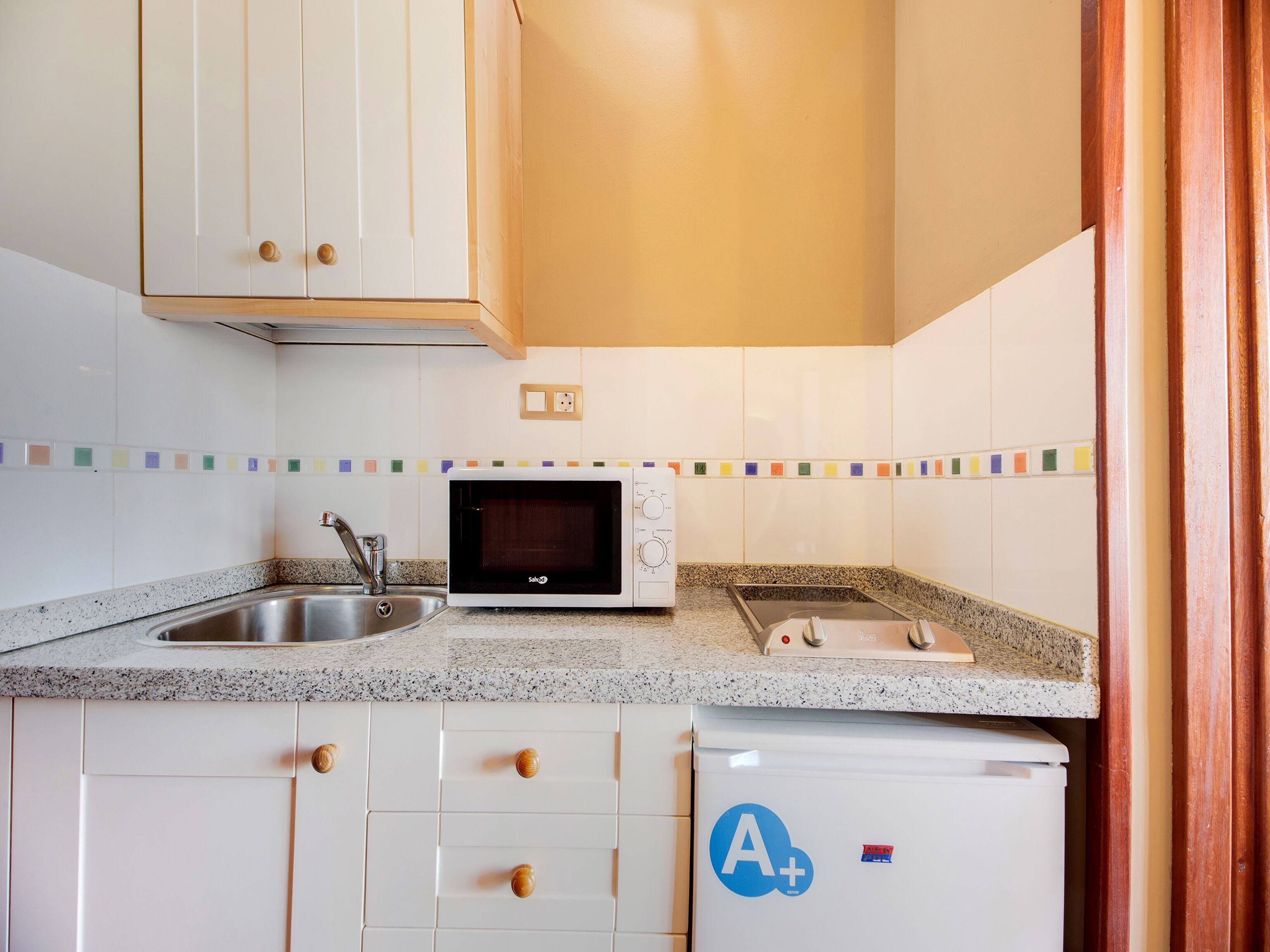 A kitchen with white cabinets, a microwave, a sink, and a refrigerator.