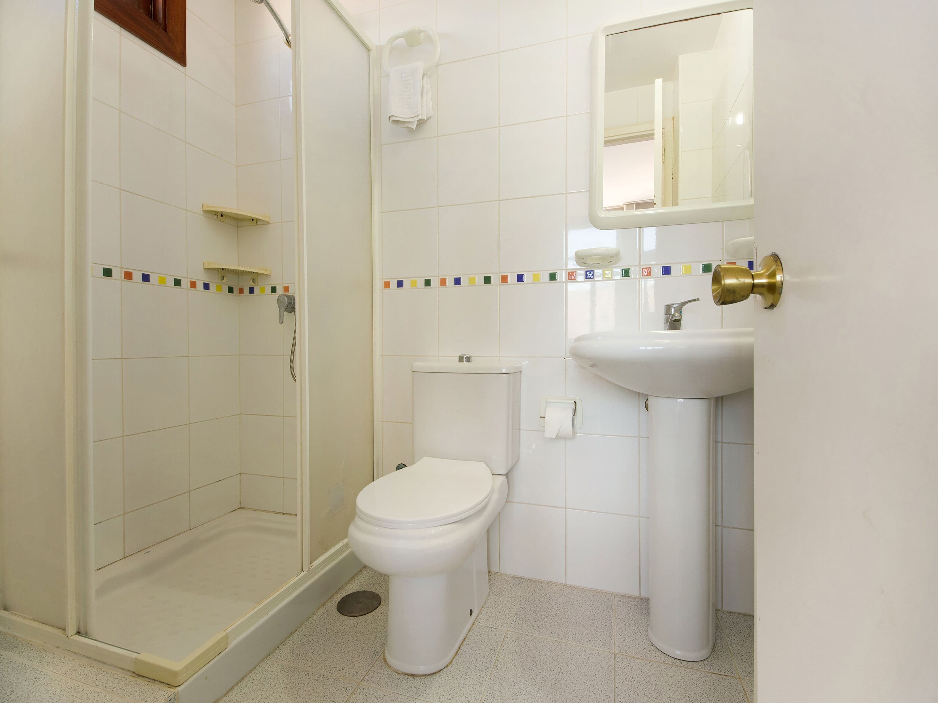 Een badkamer met douche, toilet en wastafel.