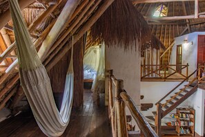 A wooden staircase with a bookcase, a hammock, and a bed with a mosquito net. - Apart hotel Casaejido (Playa del Carmen)