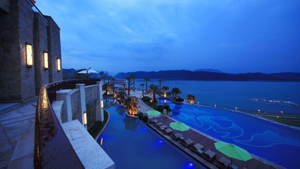 Piscina de un resort con vistas a las montañas y un cuerpo de agua.