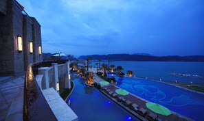 A resort pool with a view of the mountains and a body of water. - Hilton Hangzhou Qiandao Lake Resort (Hangzhou)