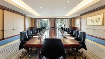 A conference room with a long table, multiple chairs, and a carpeted floor.