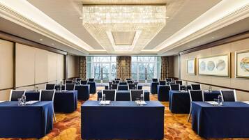 A conference room with multiple tables, chairs, and a large chandelier.