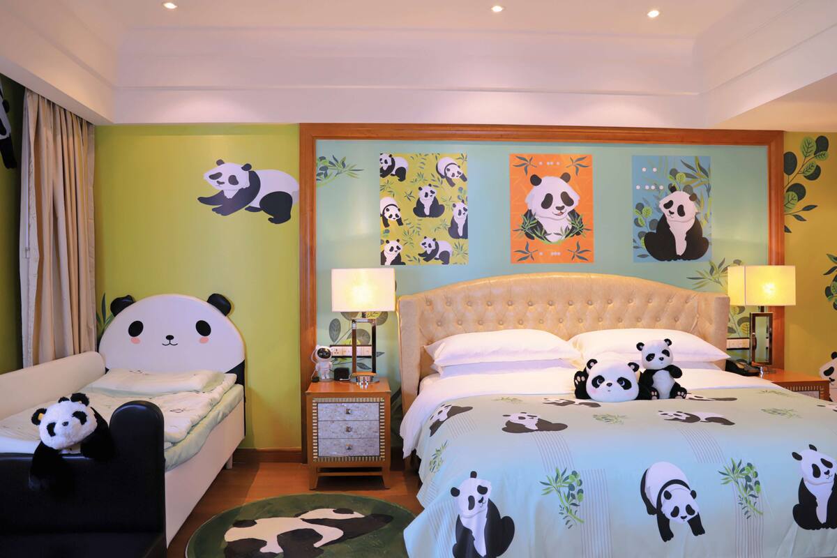 A hotel room with a bed, two nightstands, and a panda-themed bedspread.