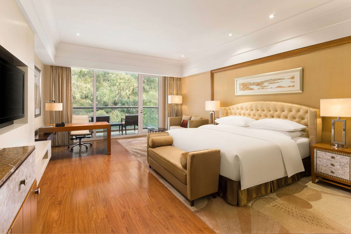 A hotel room with a large bed, a desk, a chair, and a TV.