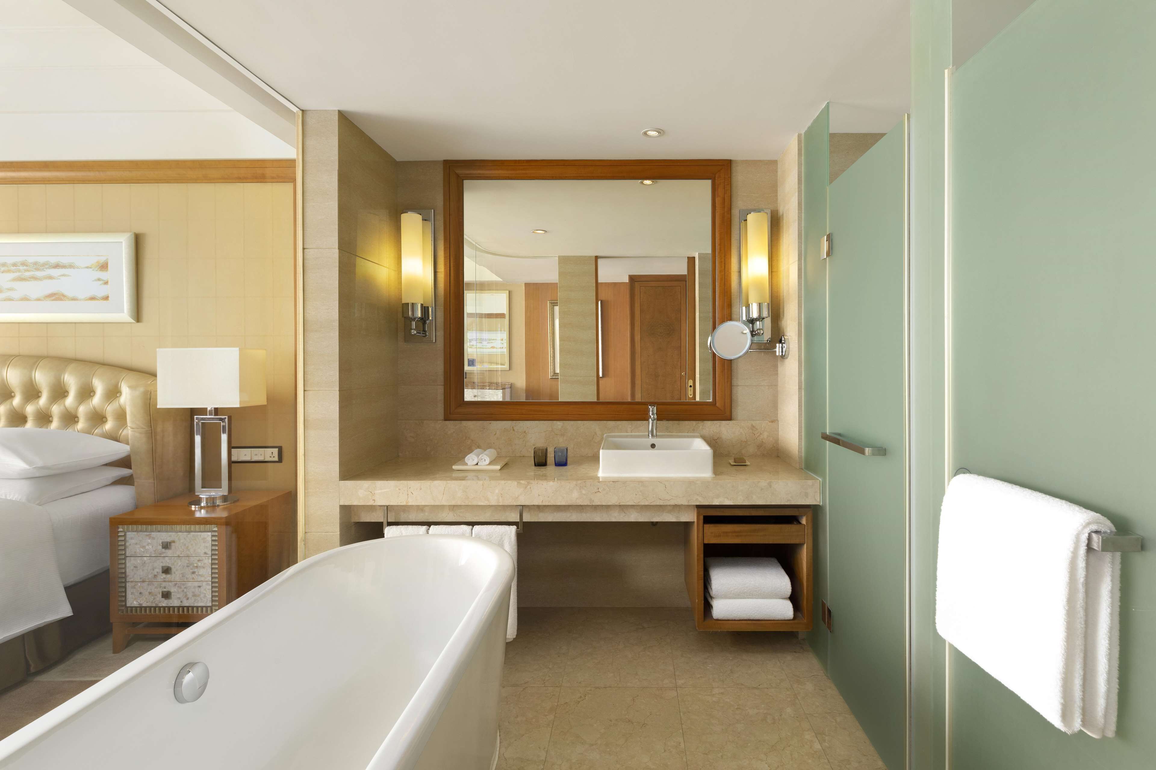 A modern bathroom with a freestanding bathtub, a vanity with a mirror, and a towel rack.