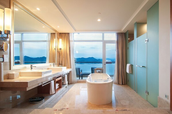 A modern bathroom with dual sinks, a large bathtub, and a view of the sea. - Hilton Hangzhou Qiandao Lake Resort (Hangzhou)