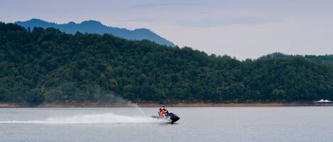 A person wakeboarding on a lake with a forested mountain in the background.